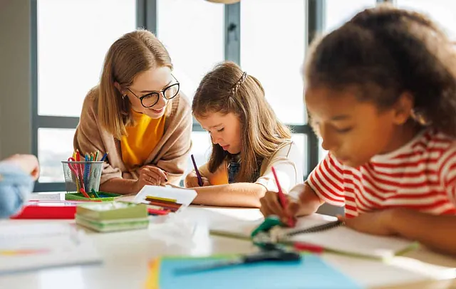Eine Frau übt mit Kindern das Schreiben